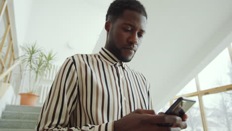 Black-Man-Standing-on-Stairs-and-Texting-on-Smartphone